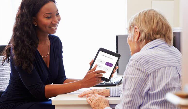 Woman showing an older woman some options on a handheld device